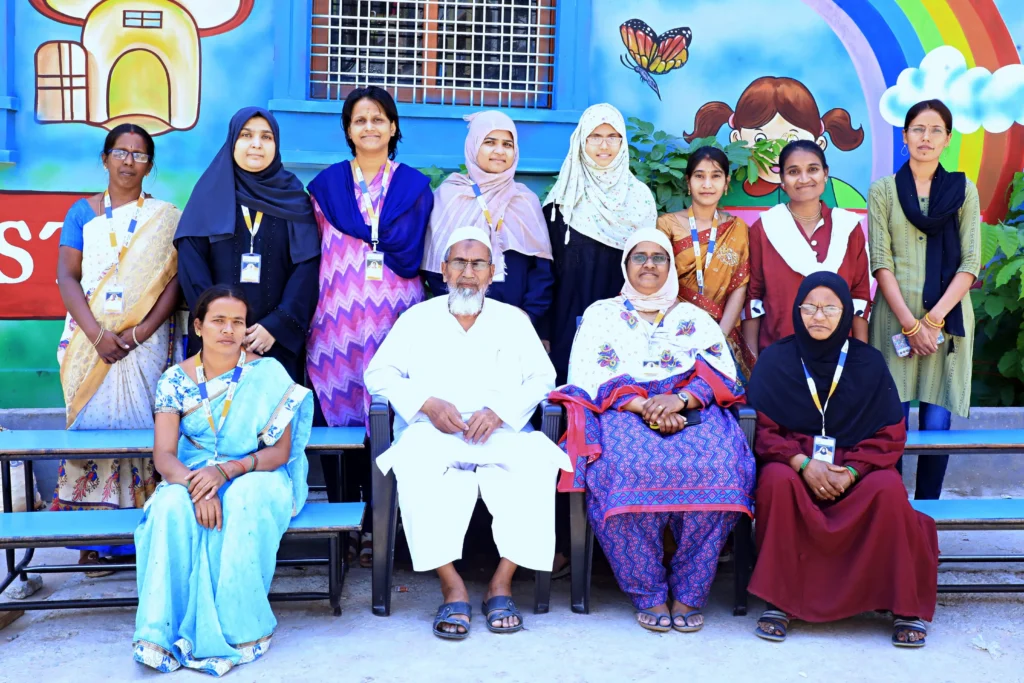 Best Techno School faculty and administrative team standing together on the school campus in front of a vibrant educational mural, showcasing the school's dedicated staff.