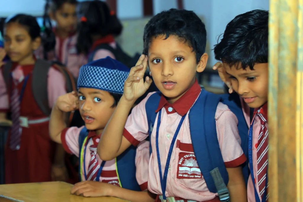 Primary school students in uniform actively participating in a classroom activity at Best Techno School, demonstrating curiosity and engagement in learning.